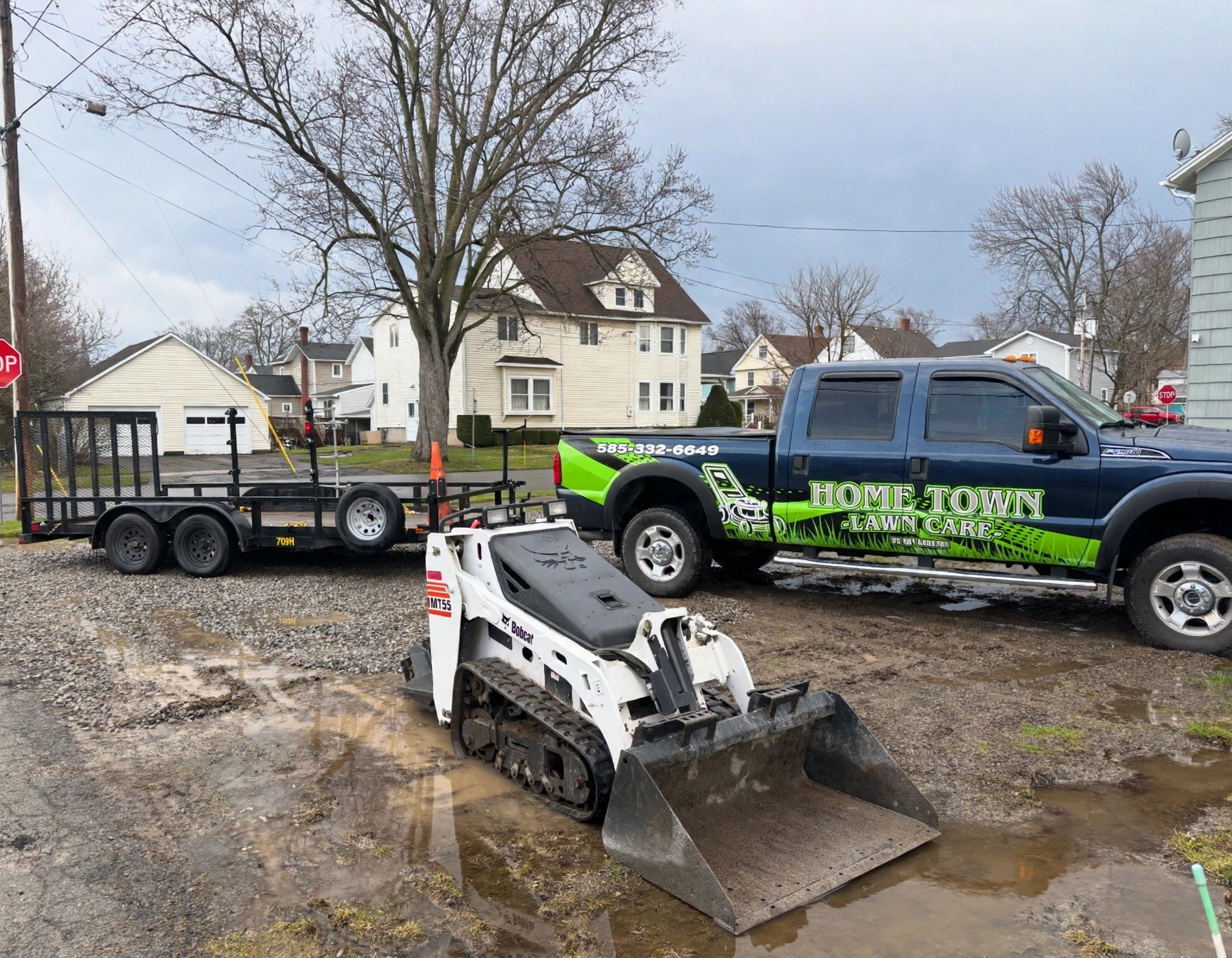 Home Town Lawn Care branded truck and Bobcat at a Medina job site